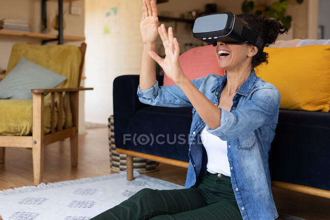 Caucasian woman smiling wearing vr headset sitting on floor at home. Staying at home in self isolation during quarantine lockdown. — Stock Photo