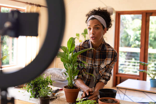 Caucasian woman, vlogging, potting plants at home. Staying at home in self isolation during quarantine lockdown. — Stock Photo