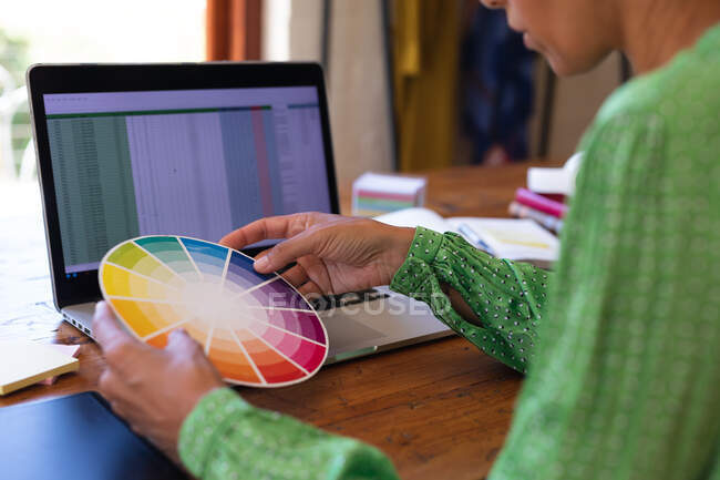 Kaukasische Frau wählt Farben, benutzt Laptop, arbeitet von zu Hause aus. Zu Hause bleiben in Selbstisolierung während Quarantäne Lockdown. — Stockfoto