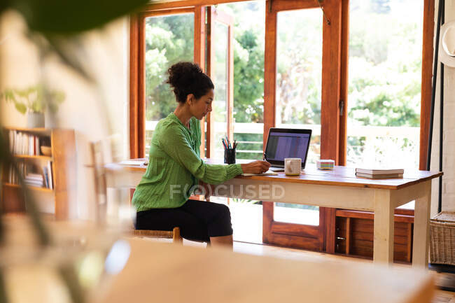 Mujer caucásica sentada en el escritorio, trabajando desde casa. Permanecer en casa en aislamiento durante el bloqueo de cuarentena. - foto de stock