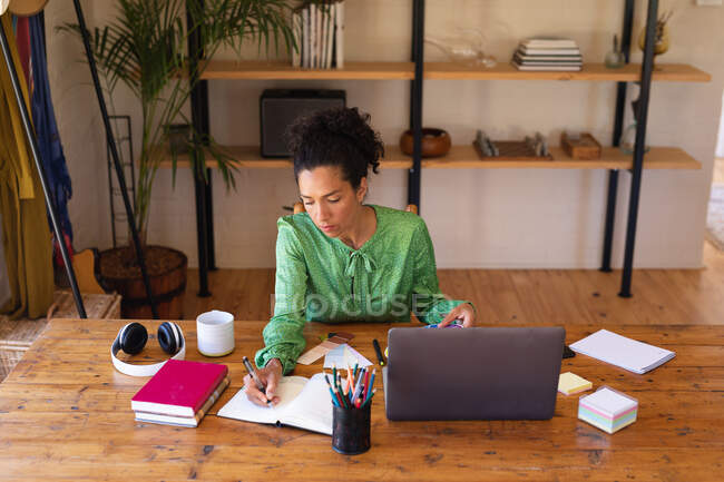 Mujer caucásica usando laptop trabajando desde casa, escribiendo. Permanecer en casa en aislamiento durante el bloqueo de cuarentena. - foto de stock