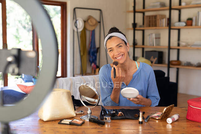 Mulher branca sorridente, vlogging, aplicação de maquiagem, usando escova de maquiagem em casa. Ficar em casa em auto-isolamento durante o bloqueio de quarentena. — Fotografia de Stock