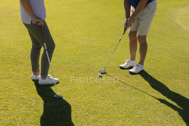 Старший мужчина и женщина готовятся к выстрелу на зеленой. гольф-спортивное хобби, здоровый пенсионный образ жизни. — стоковое фото