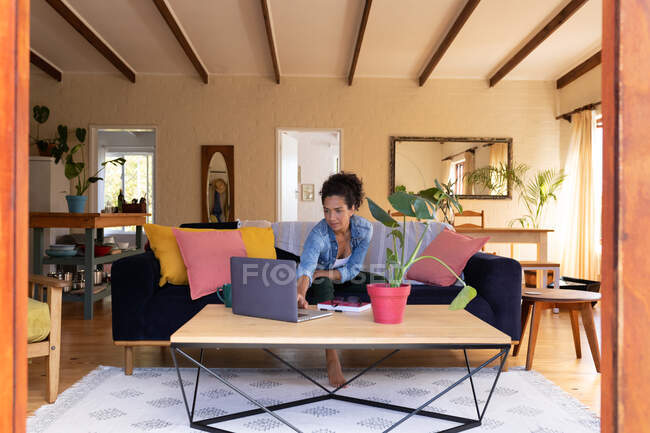 Белая женщина с ноутбуком, сидит дома на диване. Оставаться дома в изоляции во время карантинной изоляции. — стоковое фото