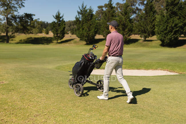 Homme âgé caucasien marchant sur le terrain de golf tenant sac de golf. Golf passe-temps sportif, mode de vie sain à la retraite — Photo de stock