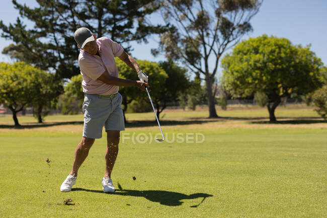 Un aîné caucasien tenant un club de golf tirant sur le vert. golf passe-temps sportif, mode de vie sain à la retraite. — Photo de stock