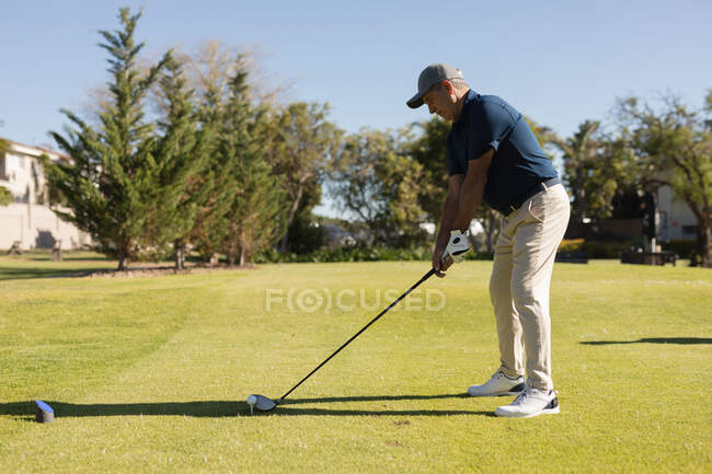 Hombre mayor caucásico sosteniendo club de golf preparándose para el tiro en el green. Golf deportes hobby, estilo de vida de jubilación saludable. - foto de stock