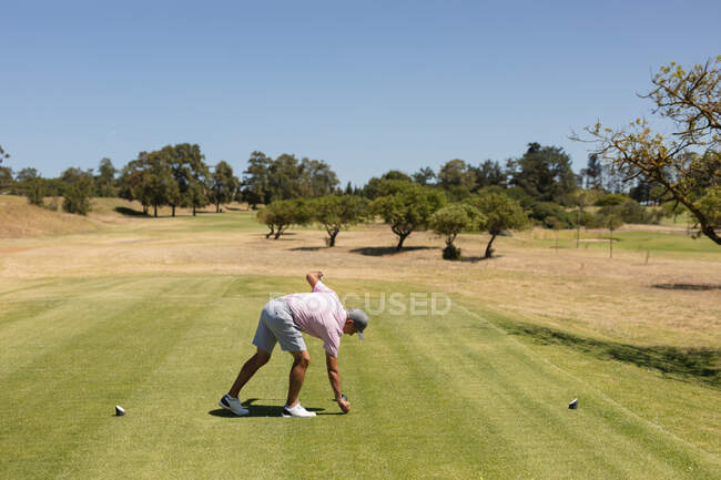 Hombre mayor caucásico sosteniendo club de golf preparando la pelota para el tiro en el green. Golf deportes hobby, estilo de vida de jubilación saludable. - foto de stock