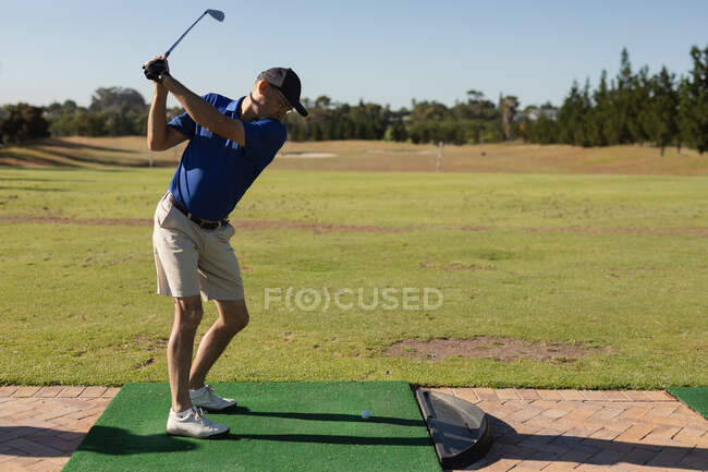 Старший европеец держит клюшку для гольфа, готовясь к выстрелу на лужайке. Спортивное увлечение гольфом, здоровый пенсионный образ жизни. — стоковое фото