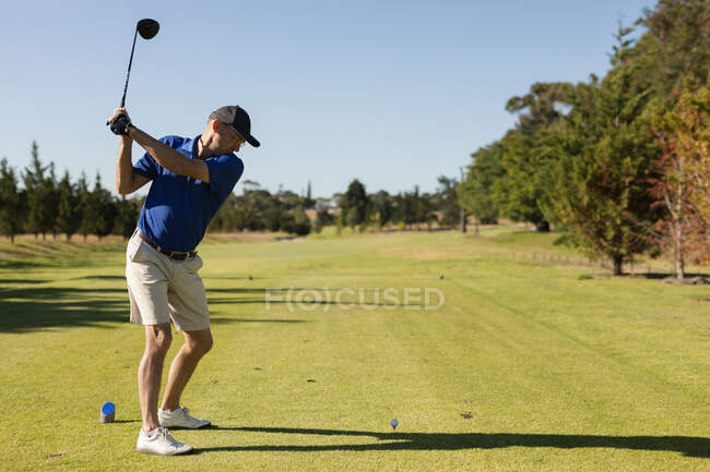 Старший европеец держит клюшку для гольфа, готовясь к выстрелу на лужайке. Спортивное увлечение гольфом, здоровый пенсионный образ жизни. — стоковое фото