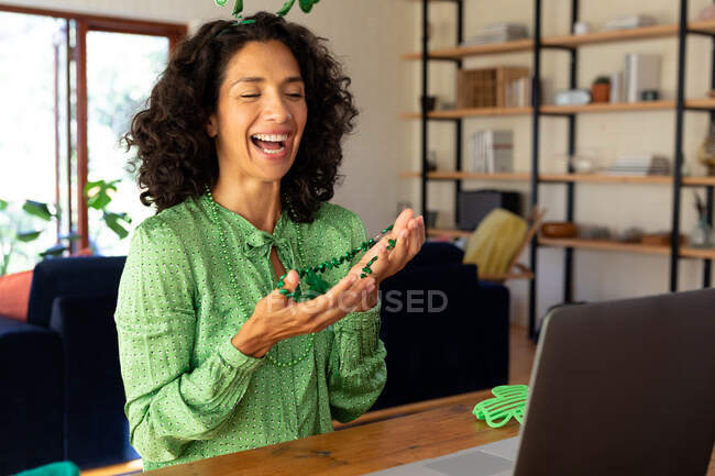 Kaukasische Frau in grün für st patrick 's day lachen während Videoanruf gekleidet. Zu Hause bleiben in Selbstisolierung während Quarantäne Lockdown. — Stockfoto