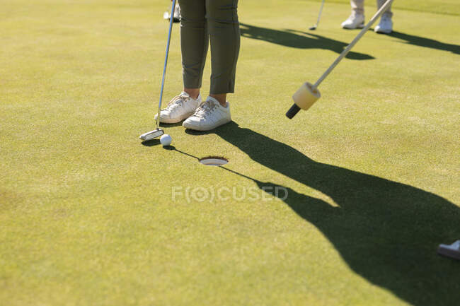 Старша жінка тримає гольф-клуб, готуючись до пострілу на зеленому. Гольф спортивне хобі, здоровий спосіб життя на пенсії . — стокове фото