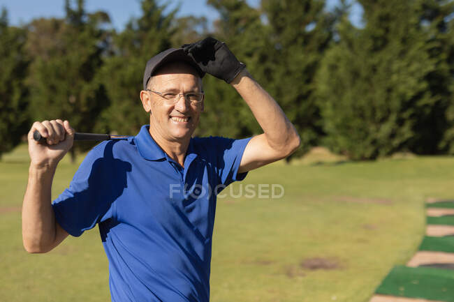 Portrait of caucasian senior man holding golf club looking at camera and smiling. golf sports hobby, healthy retirement lifestyle. — Stock Photo