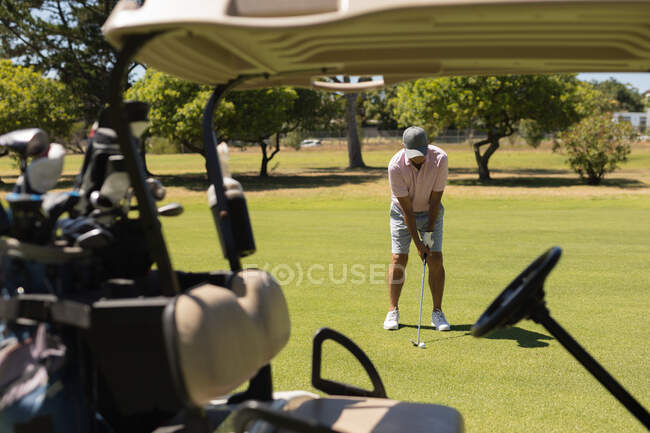Caucasian senior woman holding golf club preparing for shot on the green by the baggie. Golf sports hobby, healthy retirement lifestyle. — Stock Photo
