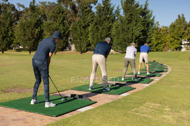 Homens e mulheres caucasianos seniores segurando clube de golfe se preparando para tiro no verde. passatempo de esportes de golfe, estilo de vida de aposentadoria saudável. — Fotografia de Stock