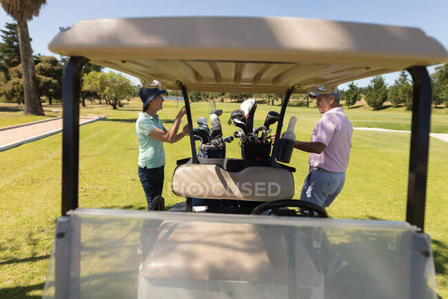 Homem e mulher caucasianos a tirar tacos de golfe de sacos de golfe no saco. passatempo de esportes de golfe, estilo de vida de aposentadoria saudável. — Fotografia de Stock