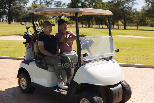 Caucasiano homem sênior e mulher dirigindo buggy de golfe no campo de golfe falando e sorrindo. Esportes de golfe passatempo, estilo de vida de aposentadoria saudável. — Fotografia de Stock