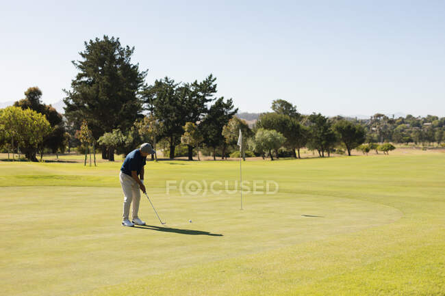 Kaukasischer Senior mit Golfschläger bereitet sich auf den Schlag auf dem Grün vor. Golf-Sport-Hobby, gesunder Lebensstil im Ruhestand. — Stockfoto