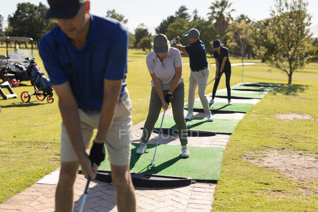 Three caucasian senior man and one woman holding golf club preparing for shot on the green. Golf sports hobby, healthy retirement lifestyle. — Stock Photo