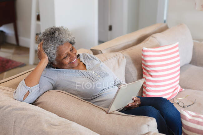 African american senior woman smiling while having a video call on digital tablet at home. staying at home in self isolation in quarantine lockdown — Stock Photo