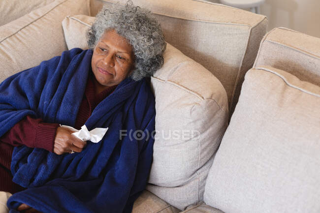 Una donna anziana afroamericana malata seduta sul divano. stare a casa in isolamento personale in quarantena — Foto stock