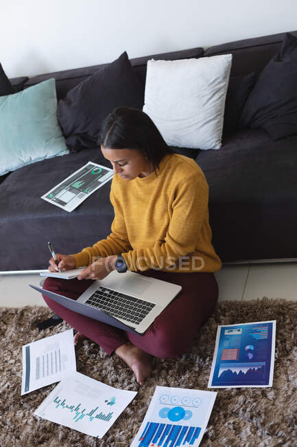 African american woman with laptop taking notes while working from home. staying at home in self isolation in quarantine lockdown — Stock Photo