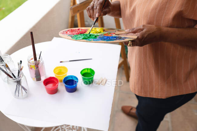 Seção média de mulher pintando em tela enquanto estava em pé no alpendre da casa. permanecer em auto-isolamento em quarentena — Fotografia de Stock