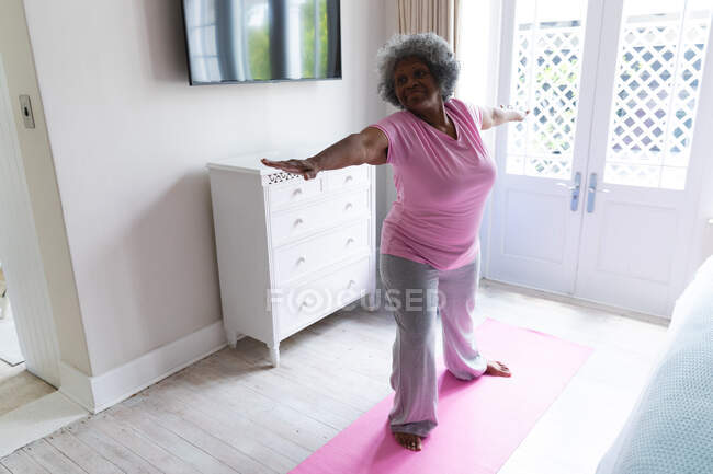 Afro-americana idosa praticando ioga em casa. ficar em casa em auto-isolamento em quarentena — Fotografia de Stock