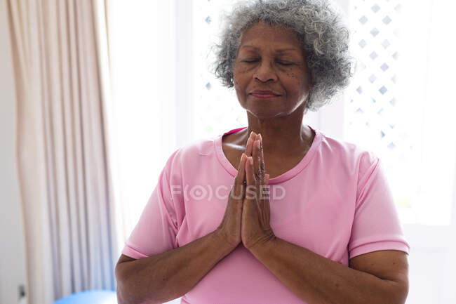 Африканская старшая женщина, практикующая йогу и медитирующая дома. оставаться дома в изоляции в карантинной изоляции — стоковое фото