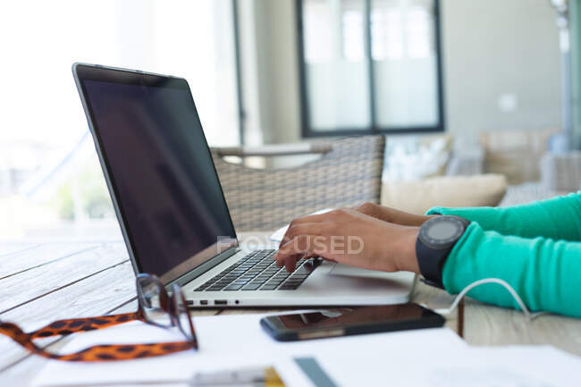 Sección media de la mujer que usa el ordenador portátil mientras trabaja desde casa. permaneciendo en casa en aislamiento en cuarentena - foto de stock