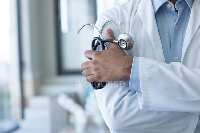Чоловічий лікар тримає стетоскоп. професійний медичний працівник носить стетоскоп та лабораторне пальто . — стокове фото