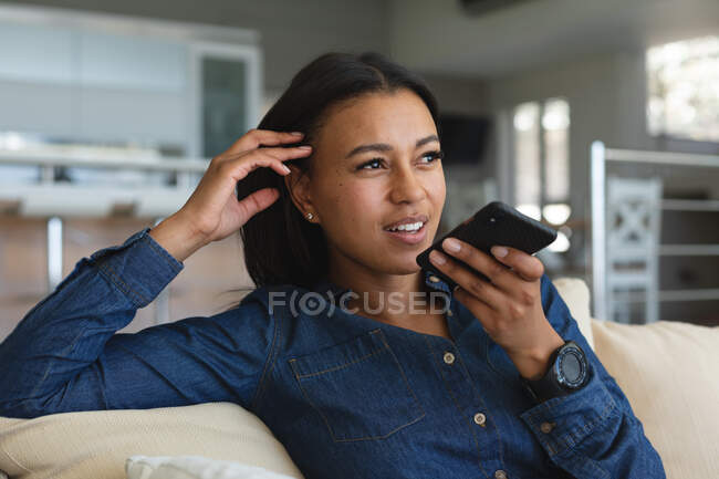 Afroamerikanerin im Smartphone-Gespräch, während sie zu Hause auf der Couch sitzt. Zu Hause bleiben in Selbstisolierung in Quarantäne — Stockfoto