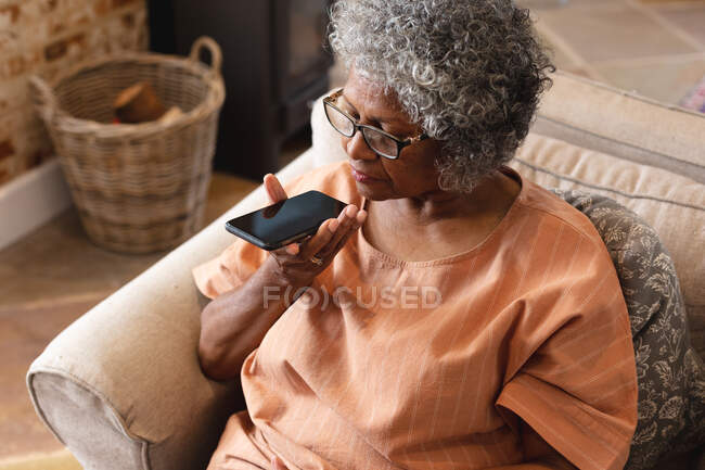 Nachdenkliche afrikanisch-amerikanische Seniorin, die zu Hause mit dem Smartphone spricht. Zu Hause bleiben in Selbstisolierung in Quarantäne — Stockfoto