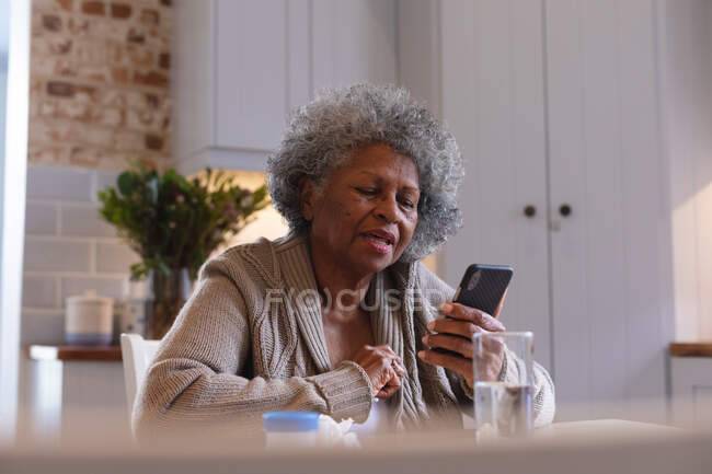 Afroamerikanische Seniorin mit Smartphone zu Hause. Zu Hause bleiben in Selbstisolierung in Quarantäne — Stockfoto