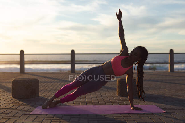 Afroamerikanerin beim Yoga an der Strandpromenade. Fitness und gesunder Lebensstil im Freien. — Stockfoto