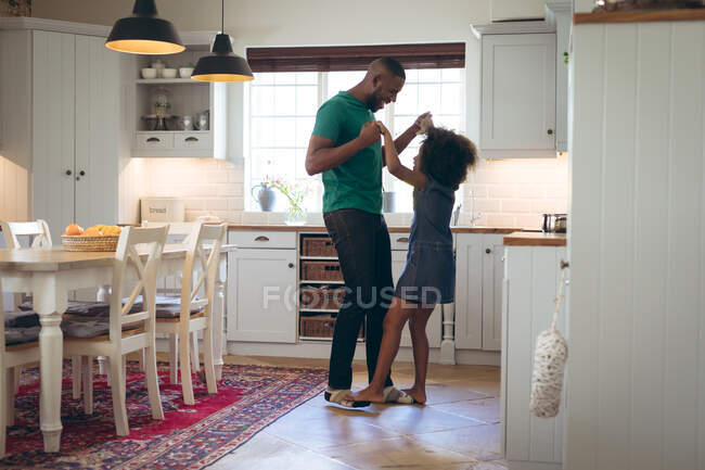 African american girl and her father embracing in kitchen. staying at home in self isolation during quarantine lockdown. — Stock Photo