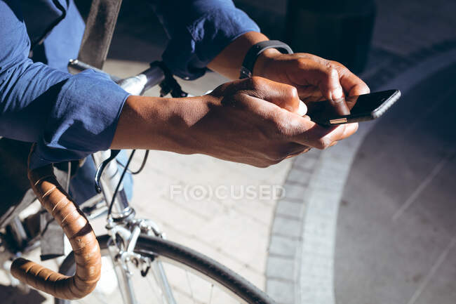 Порожнеча афроамериканського старшого чоловіка, що спирається на велосипед на вулиці за допомогою смартфона. цифровий кочівник і близько в місті під час пандемії коронавірусу 19 . — стокове фото