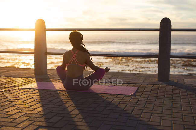 Afroamerikanerin beim Yoga an der Strandpromenade. Fitness und gesunder Lebensstil im Freien. — Stockfoto