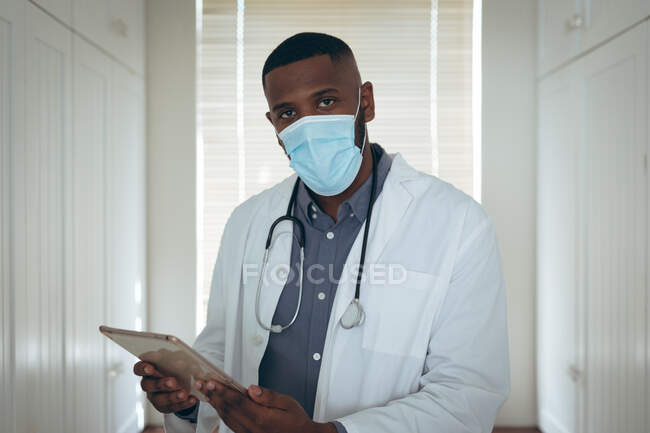 Porträt eines afrikanisch-amerikanischen Arztes mit Gesichtsmaske mittels digitalem Tablet. Während der Quarantäne zu Hause bleiben und sich selbst isolieren. — Stockfoto