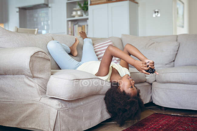 Afroamerikaner liegt auf einer Couch und spielt Videospiele. Während der Quarantäne zu Hause bleiben und sich selbst isolieren. — Stockfoto