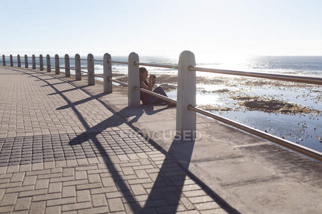 Glückliche afrikanisch-amerikanische Frau beim Fotografieren auf der Strandpromenade. Digitaler Nomade unterwegs. — Stockfoto