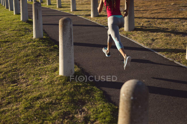 Low section of woman wearing sports clothes exercising in park jogging on path. Fitness healthy outdoor lifestyle. — Stock Photo