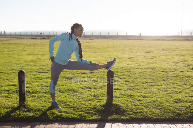 Afroamerikanerin konzentriert sich, trägt Sportkleidung und trainiert in einem Park Stretching. Fitness und gesunder Lebensstil im Freien. Ihre Beine — Stockfoto