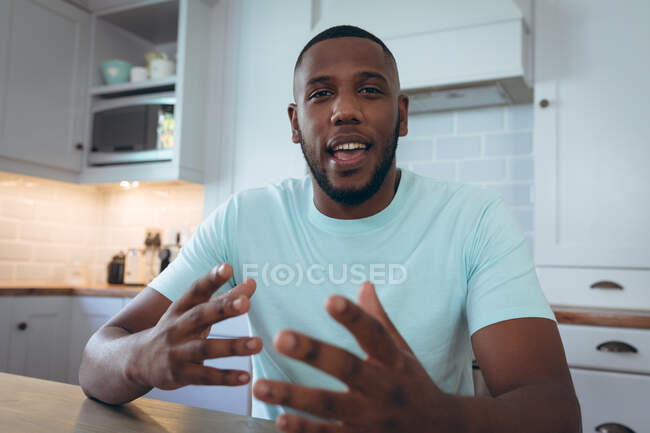 African american man sitting in kitchen having a video chat. staying at home in self isolation during quarantine lockdown. — Stock Photo