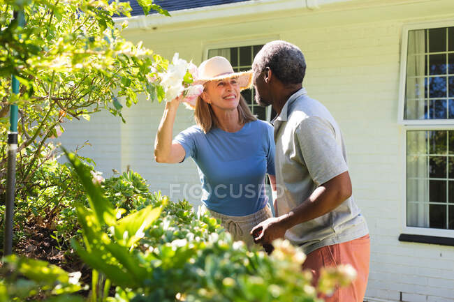 Diversi anziani coppia in giardino toccare fiori e sorridente. stare a casa in isolamento durante la quarantena. — Foto stock