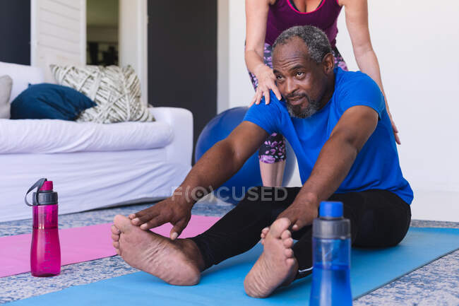 Разнообразные старшая пара упражнения сидя на ковриках йоги растяжения. оставаться дома в изоляции во время карантинной изоляции. — стоковое фото