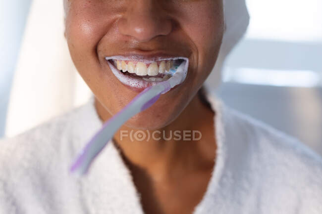 Close up of smiling african american woman with brush in her mouth. staying at home in self isolation in quarantine lockdown — Stock Photo