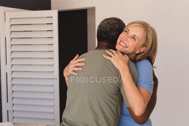 Diversa pareja de ancianos de pie abrazando y sonriendo. permanecer en casa aislado durante el bloqueo de cuarentena. - foto de stock