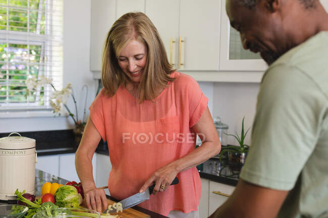 Diverse senior couple standing in kitchen and cooking dinner. staying at home in isolation during quarantine lockdown. — Stock Photo