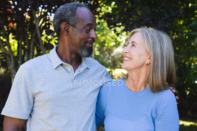 Портрет різноманітної старшої пари в саду дивиться один на одного і посміхається. перебування вдома в ізоляції під час карантину . — стокове фото